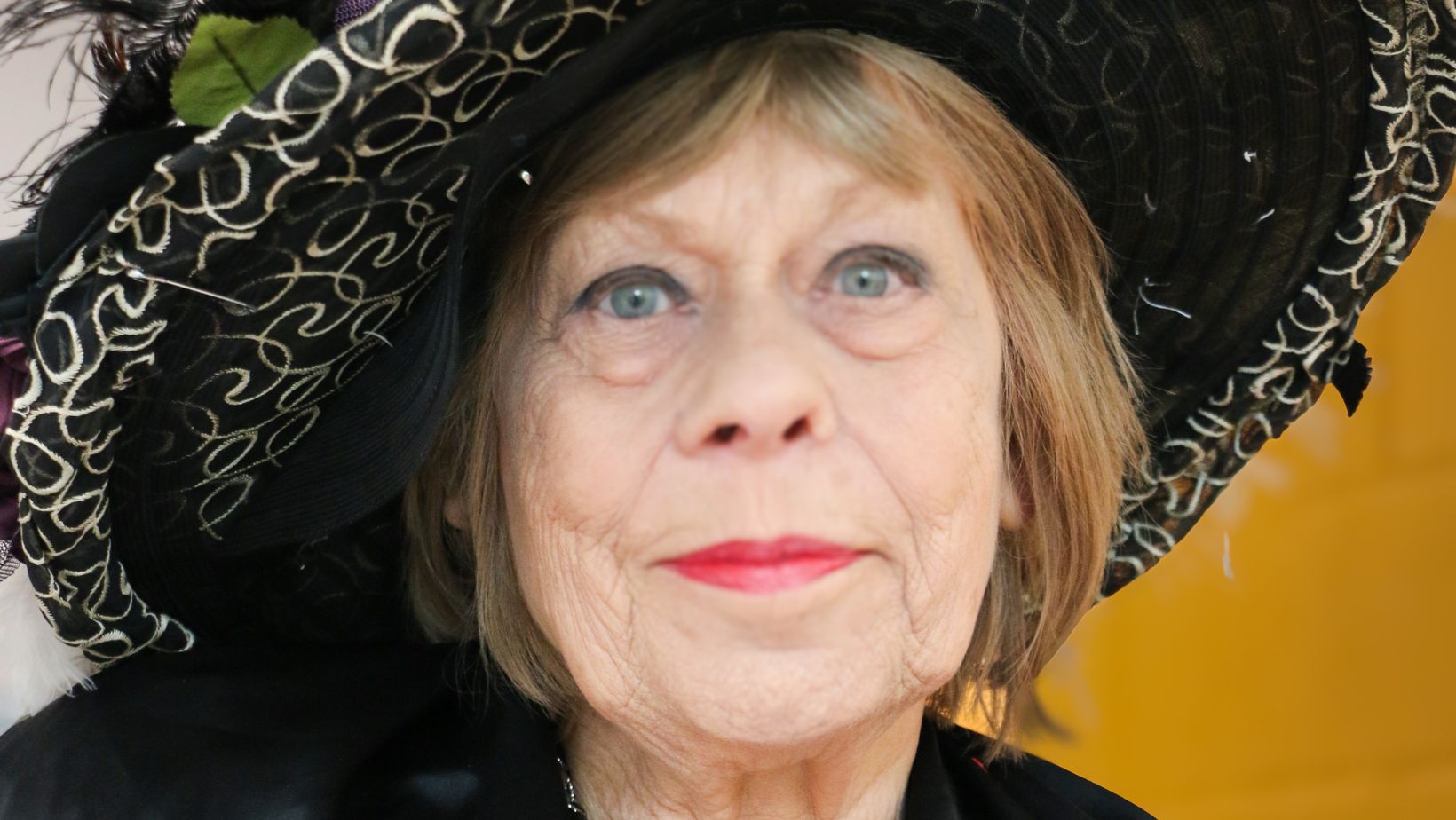 Janet Evans A woman with a large black hat looking at the camera and smiling