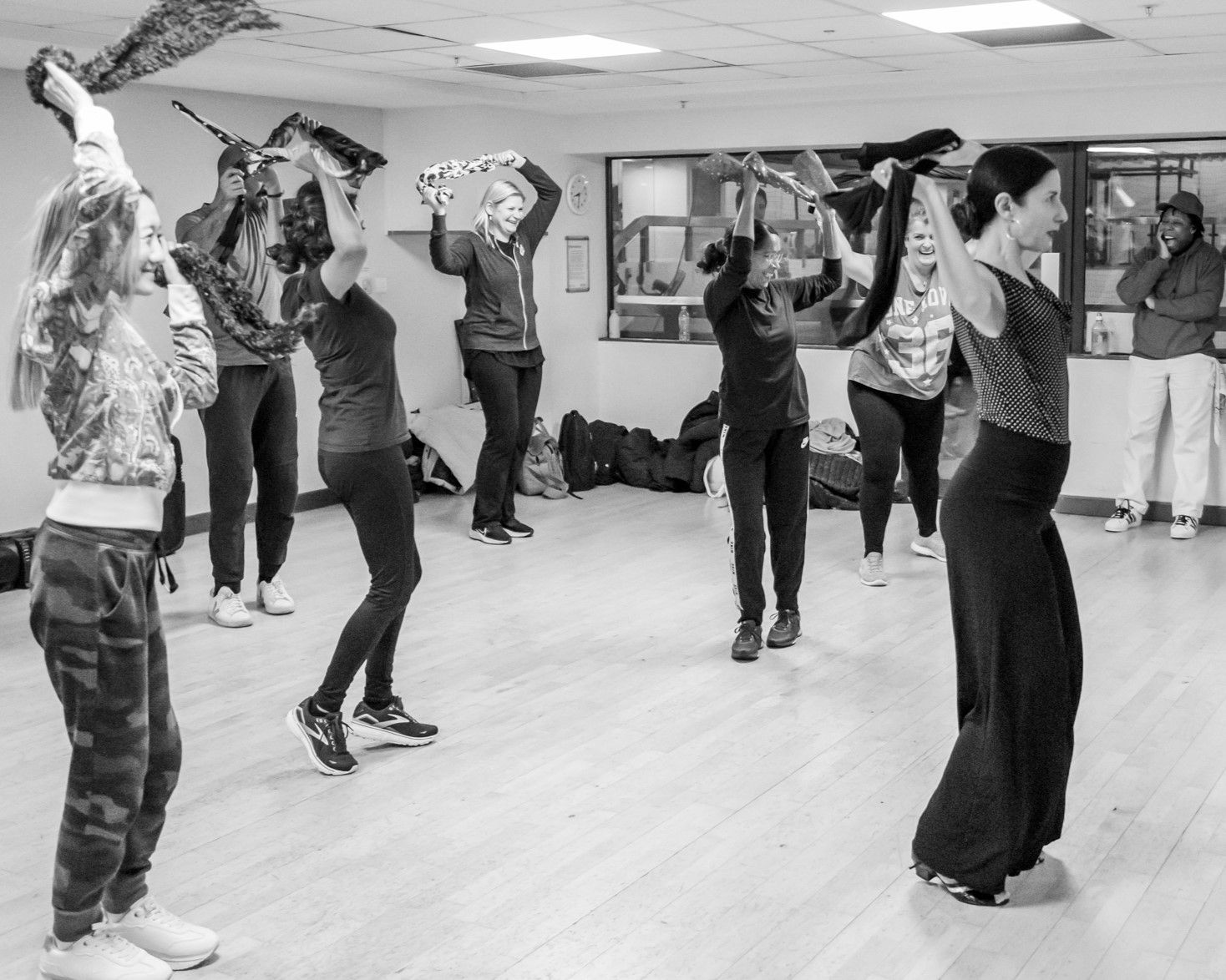 Danielle leading a session A black and white image of a group of people dancing and swirling a scarf over their heads.